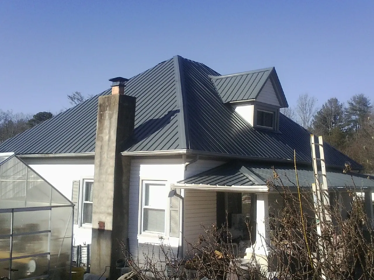 Dark blue standing seam metal roof on a white farmhouse with dormer — Slate & Tile Roof Repair by Roofing Brothers in South Dennis
