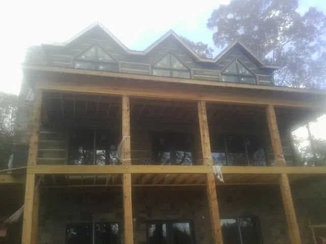 Dormers and porch framing on a large log home under construction — Roof Coating work by our crew in South Dennis