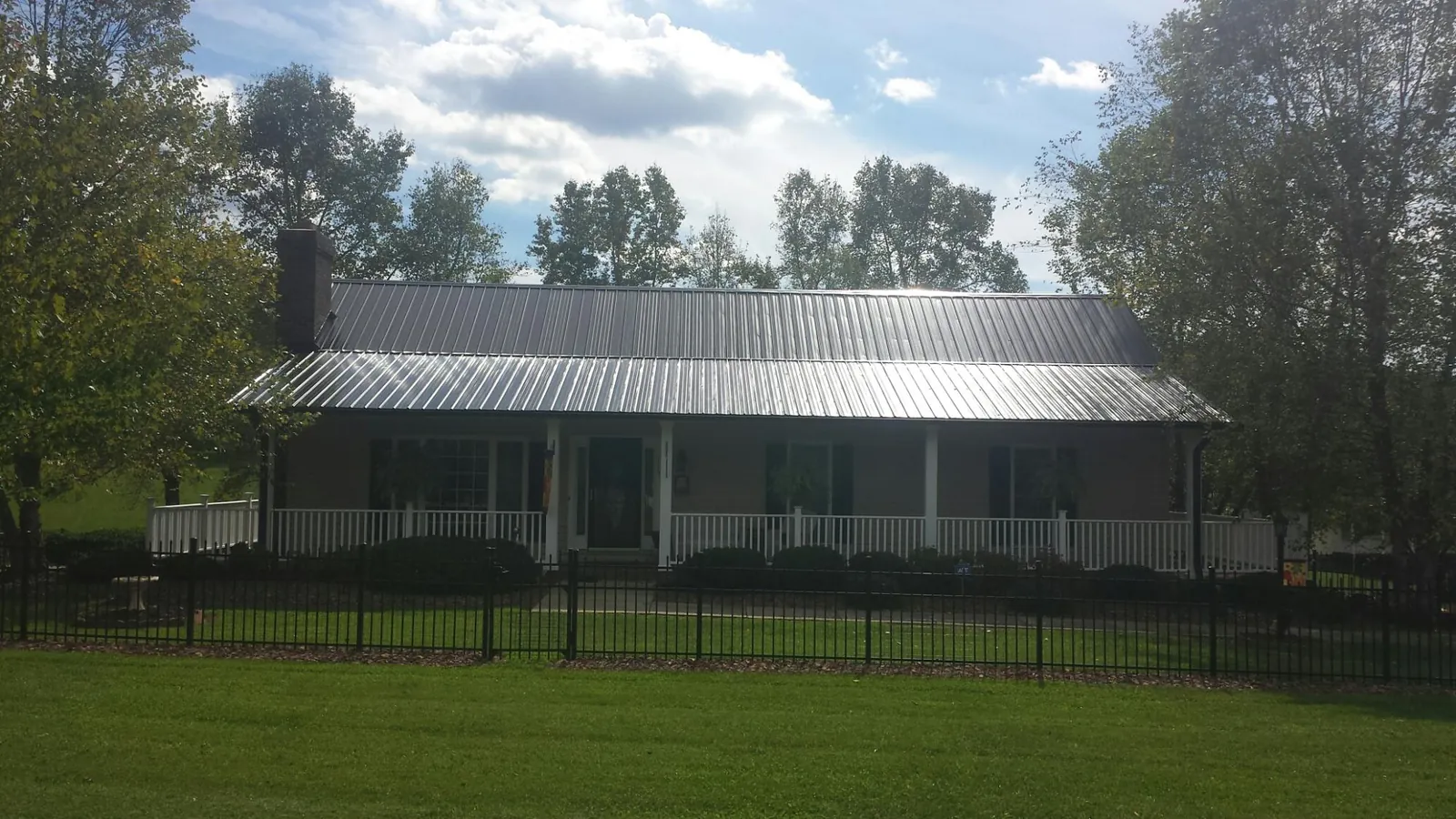 Gray metal roof on a brick ranch with a full width front porch — Gutter Guard Installation work by our crew in South Dennis