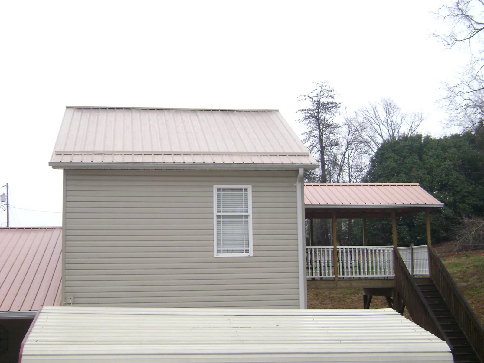 Tan metal roofs on a two story addition and attached porch, from a Roof Replacement job in South Dennis