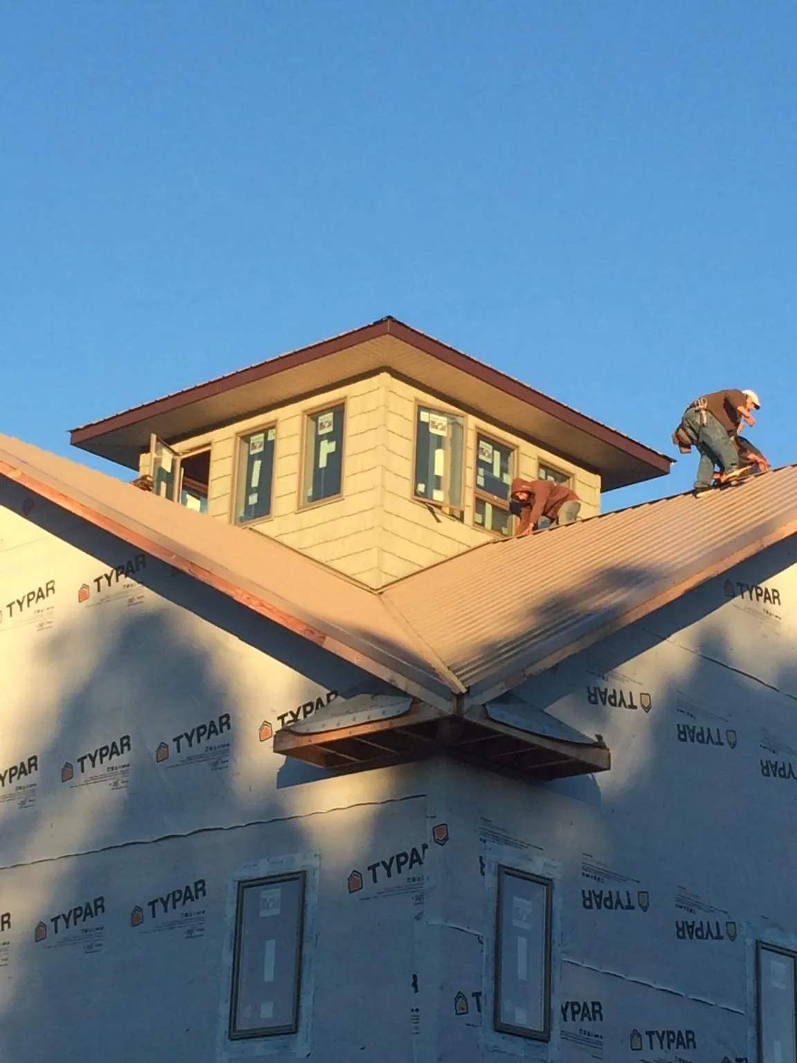 Roofers working around a rooftop cupola on a new metal roof at sunset — Roof Waterproofing in South Dennis by Roofing Brothers